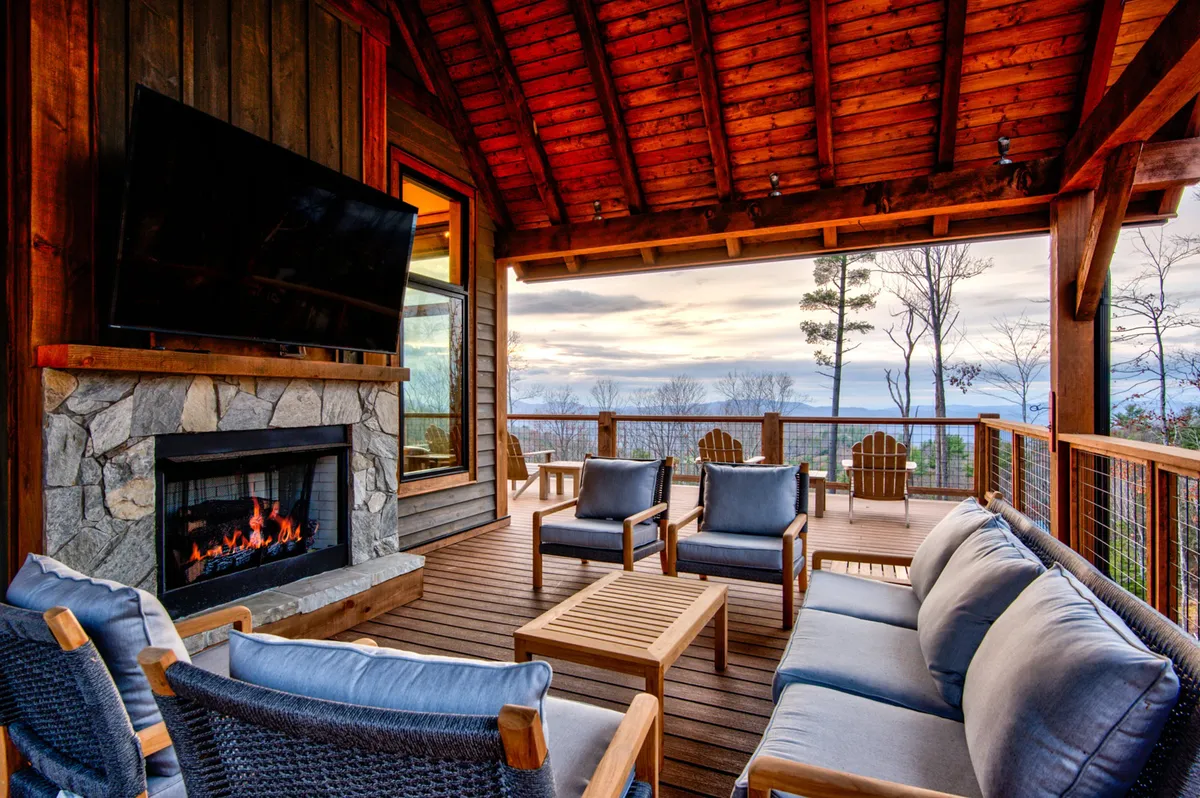 This exterior image highlights a cozy outdoor seating area centered around a fireplace, all set against a breathtaking mountain view. The warm glow of the fire and ample seating create an inviting space for evening gatherings, socializing, or simply enjoying the tranquil ambiance as the sun sets.